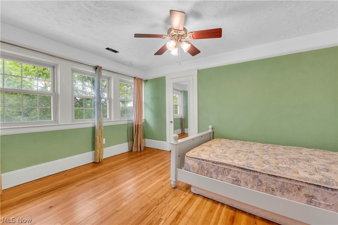 17406 Nottingham Road Cleveland, OH 44119 - Photo 31 of 45 Hardwood flooring, multiple windows, ceiling fan with light fixture, and crown molding