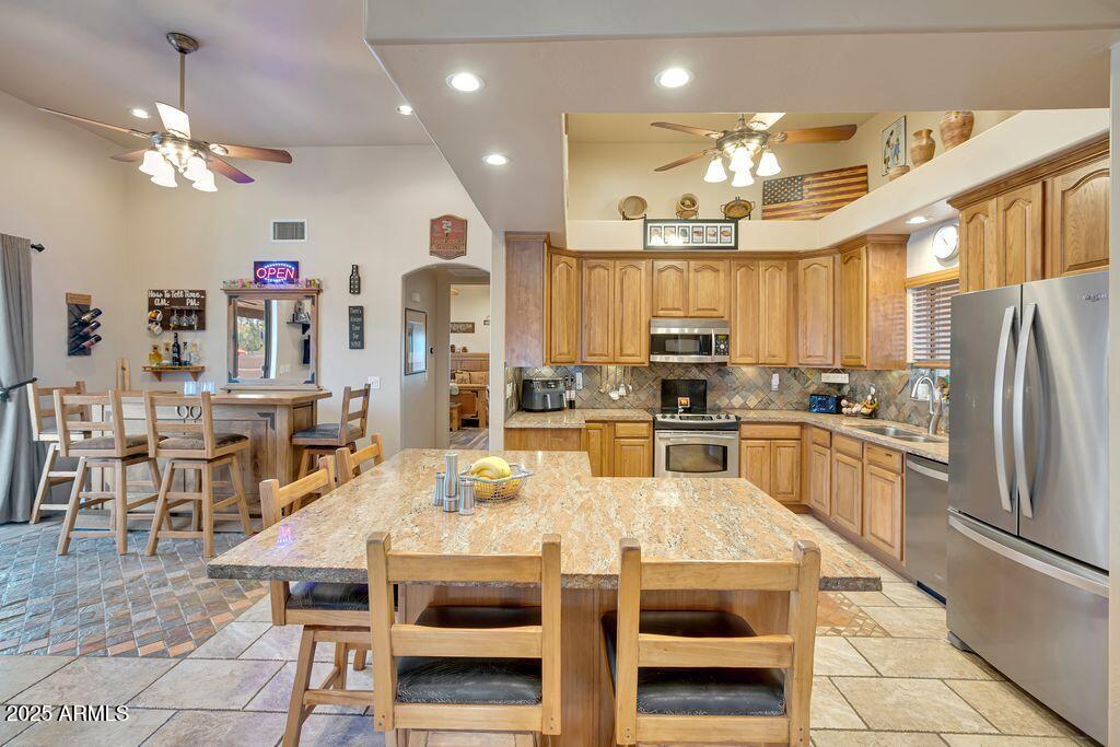 1053 East Maddock Road Phoenix, AZ 85086 - Photo 18 of 60 a kitchen with stainless steel appliances kitchen island granite countertop a refrigerator a stove a sink dishwasher and a dining table with wooden floor