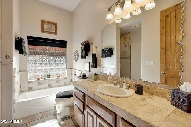 a bathroom with a granite countertop sink a large mirror and a bathtub with shower
