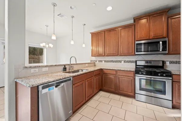 a kitchen with granite countertop a stove top oven microwave and cabinets