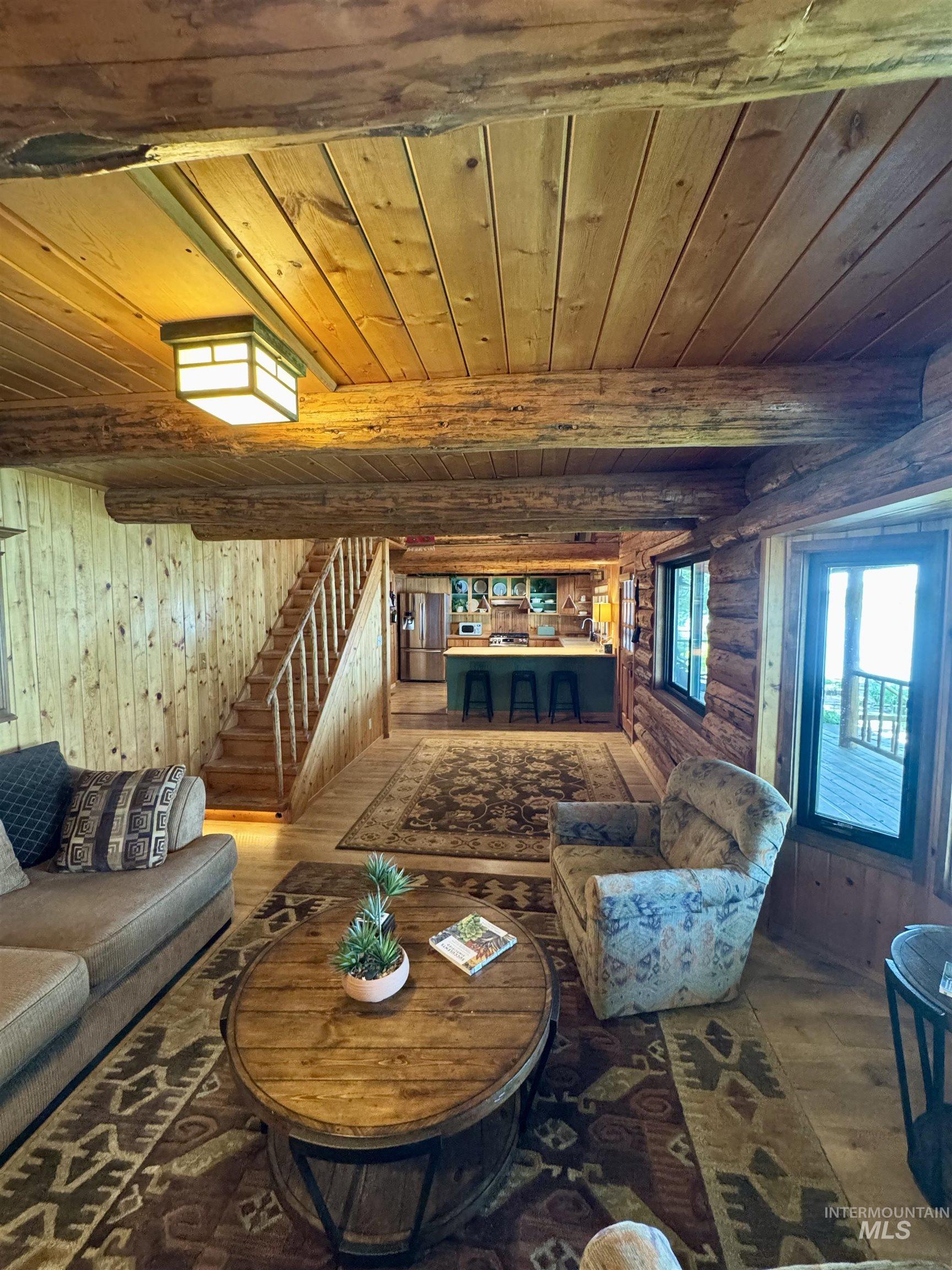 62 Bell Rapids Road Hagerman, ID 83332 - Photo 12 of 34 Open-concept living area featuring wood-finish flooring, exposed log beam ceiling, and a wooden staircase