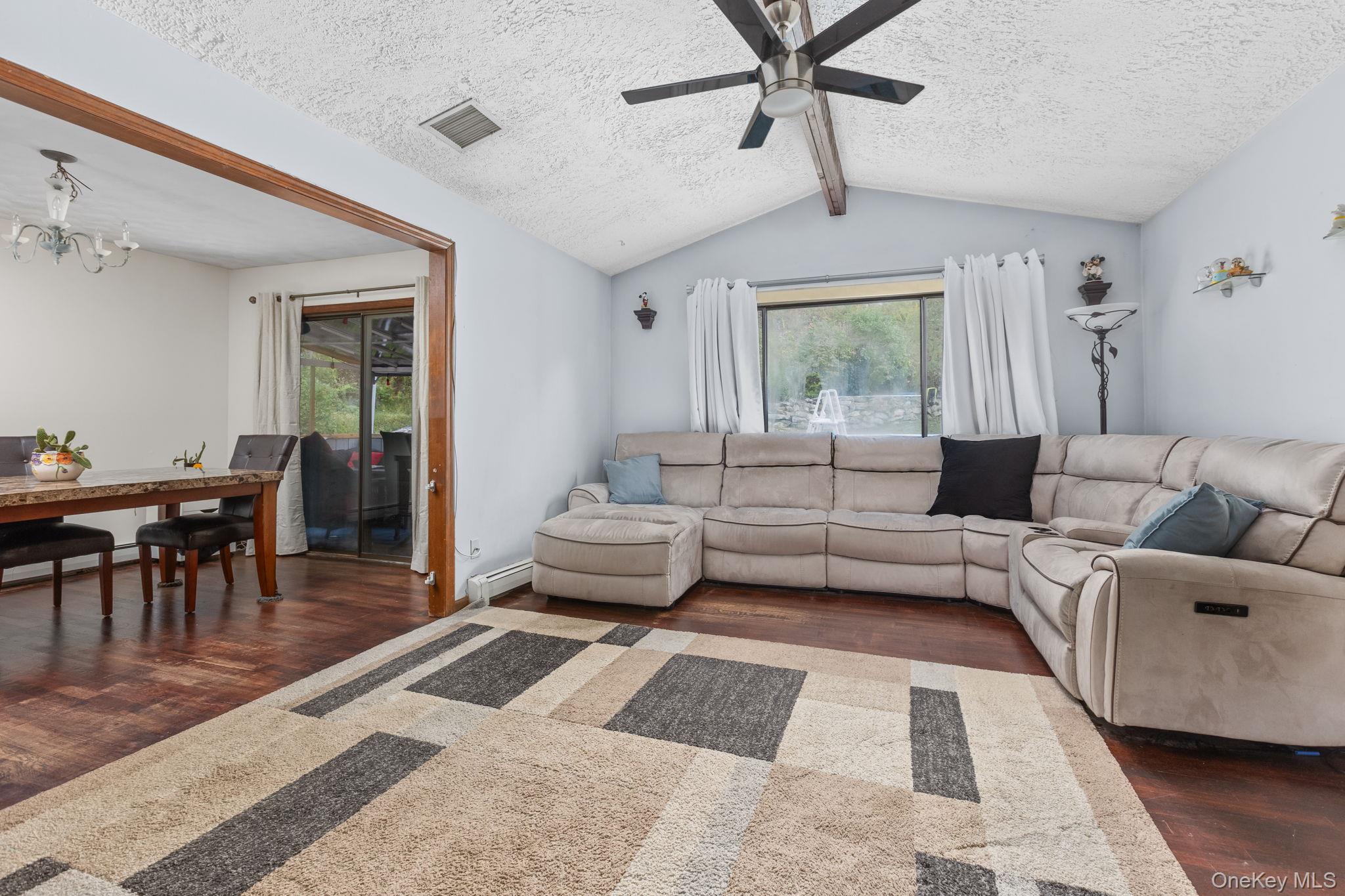 97 Old Road Brewster, NY 10509 - Photo 13 of 23 Living area with dark wood-style flooring, healthy amount of natural light, a textured ceiling, ceiling fan, and a baseboard heating unit