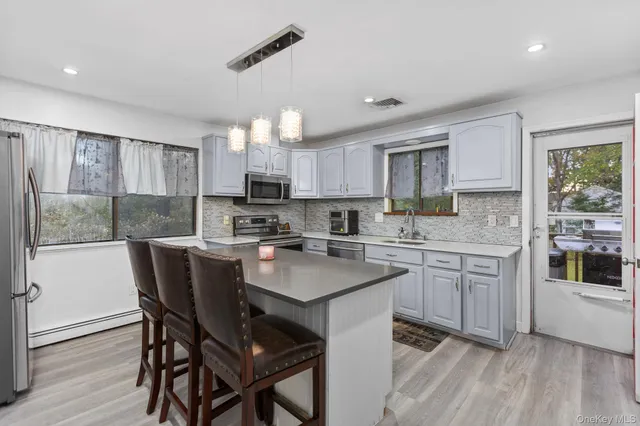 a kitchen with kitchen island granite countertop wooden floors and white cabinets