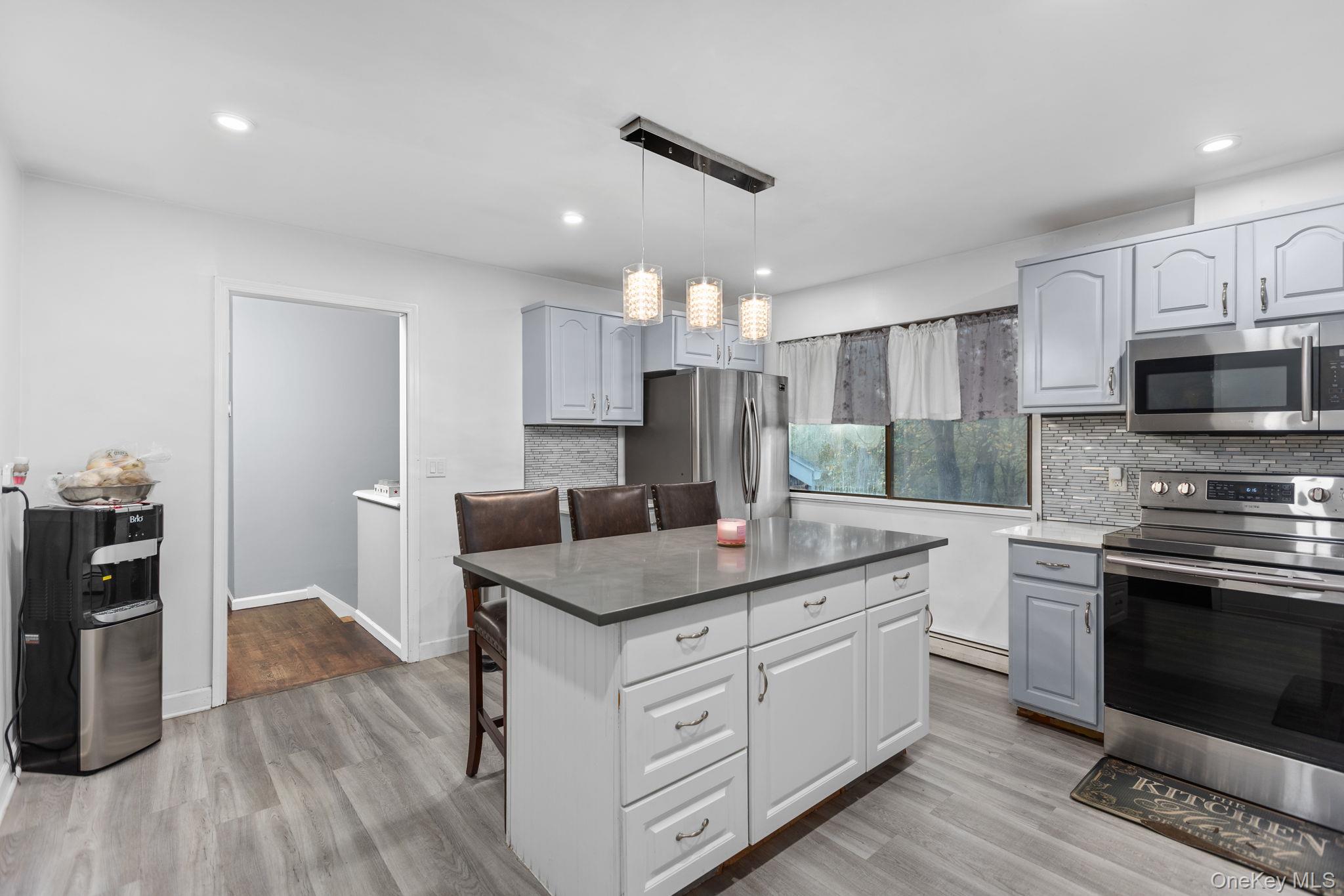 97 Old Road Brewster, NY 10509 - Photo 7 of 23 Kitchen with a kitchen bar, appliances with stainless steel finishes, backsplash, light wood-style flooring, and recessed lighting