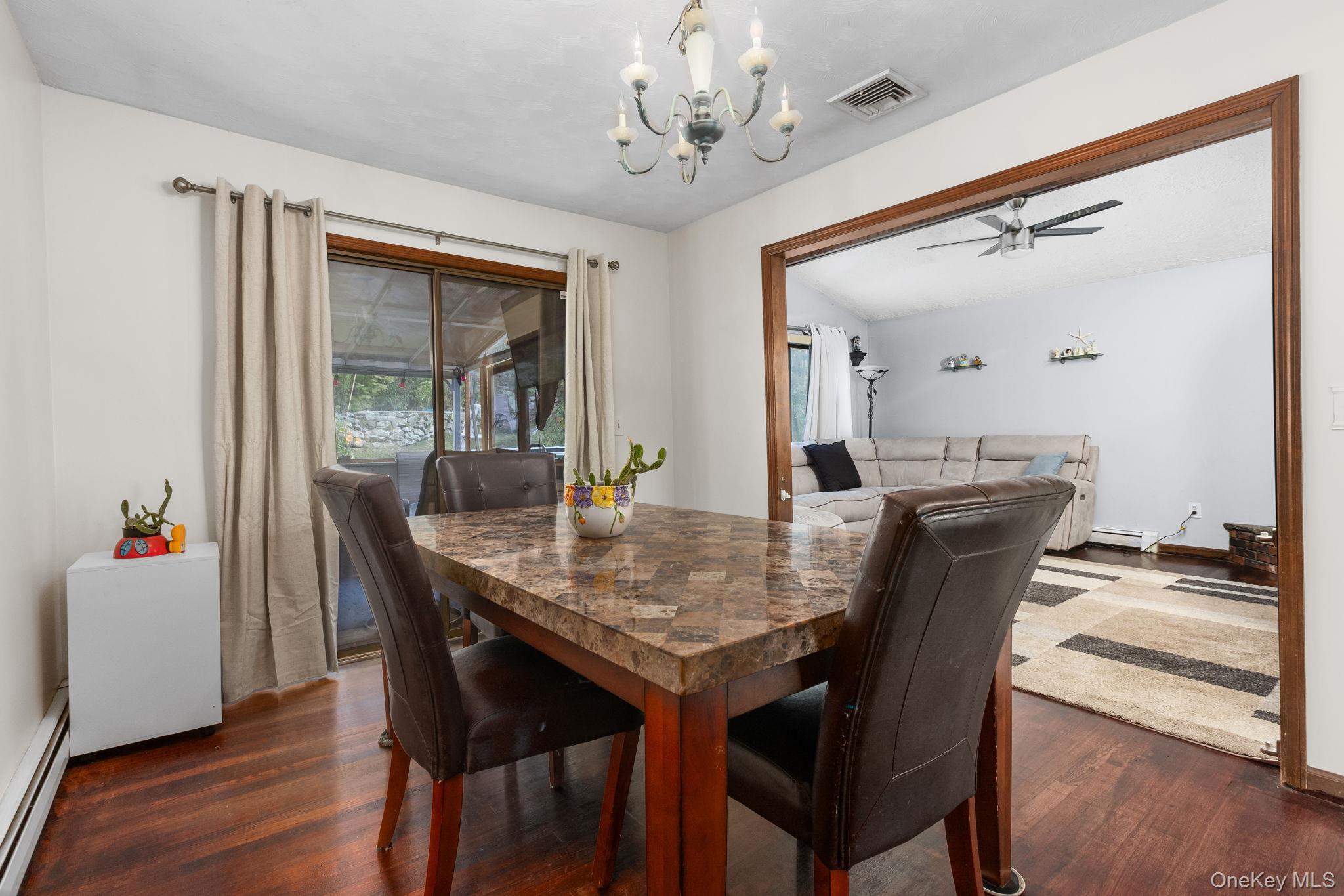 97 Old Road Brewster, NY 10509 - Photo 10 of 23 Dining area with dark wood finished floors, a baseboard radiator, a chandelier, and a ceiling fan