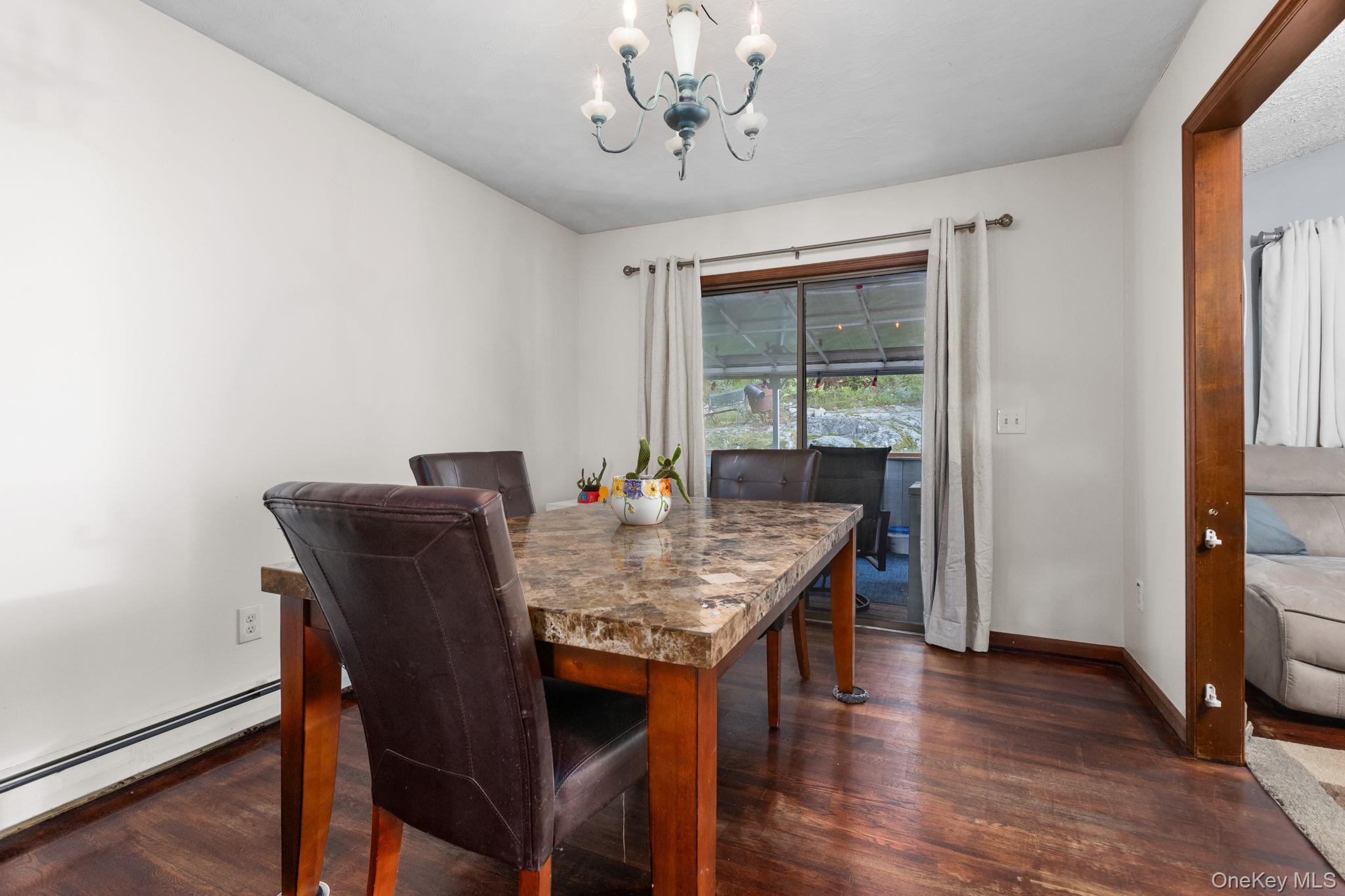 97 Old Road Brewster, NY 10509 - Photo 10 of 23 Dining area with a baseboard heating unit, dark wood-type flooring, and a chandelier