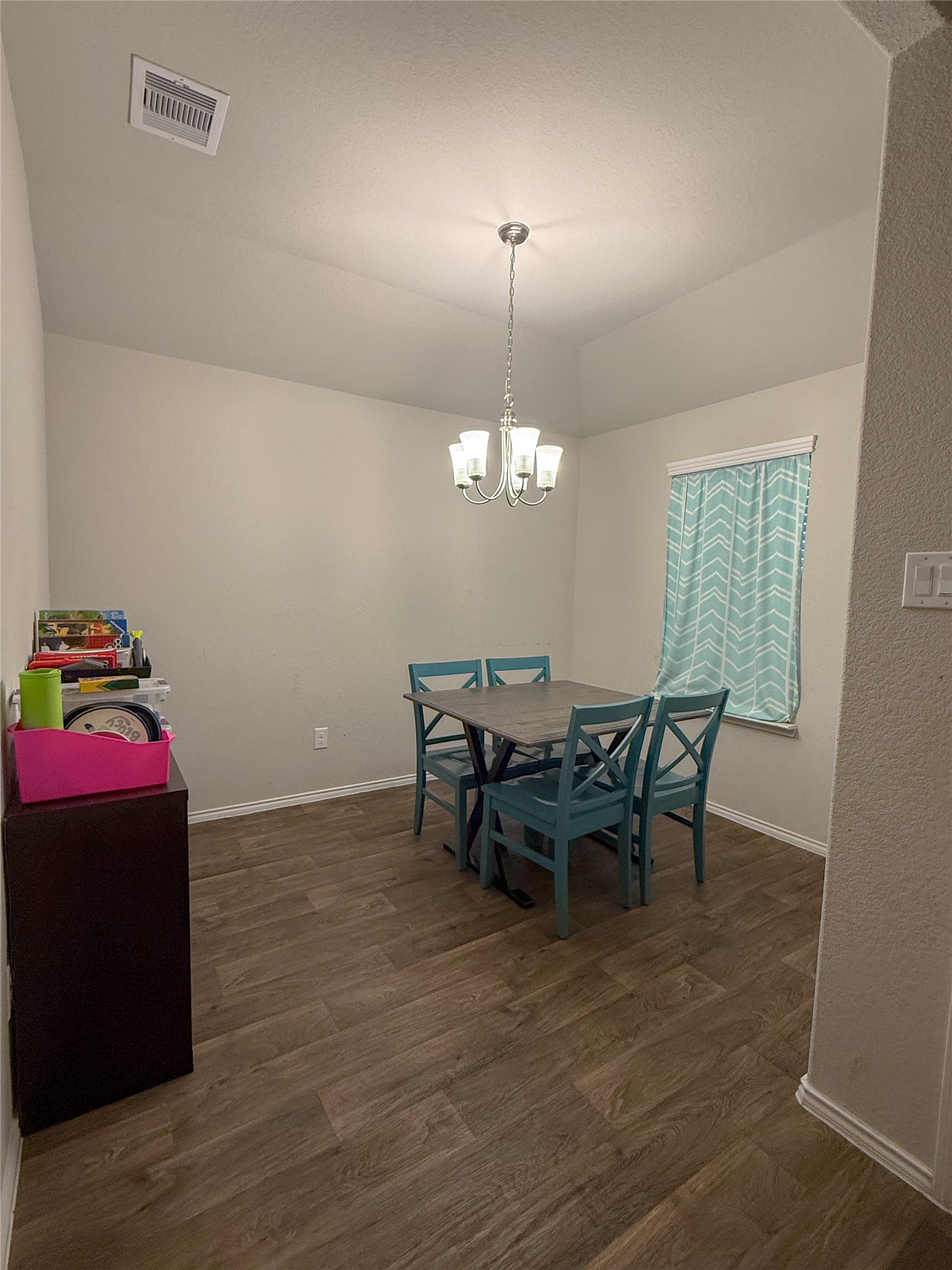 706 Zinnia Court Rosharon, TX 77583 - Photo 5 of 13 Cozy dining area with wood-like flooring, a modern chandelier, and a window overlooking the front yard. Ideal space for intimate gatherings.