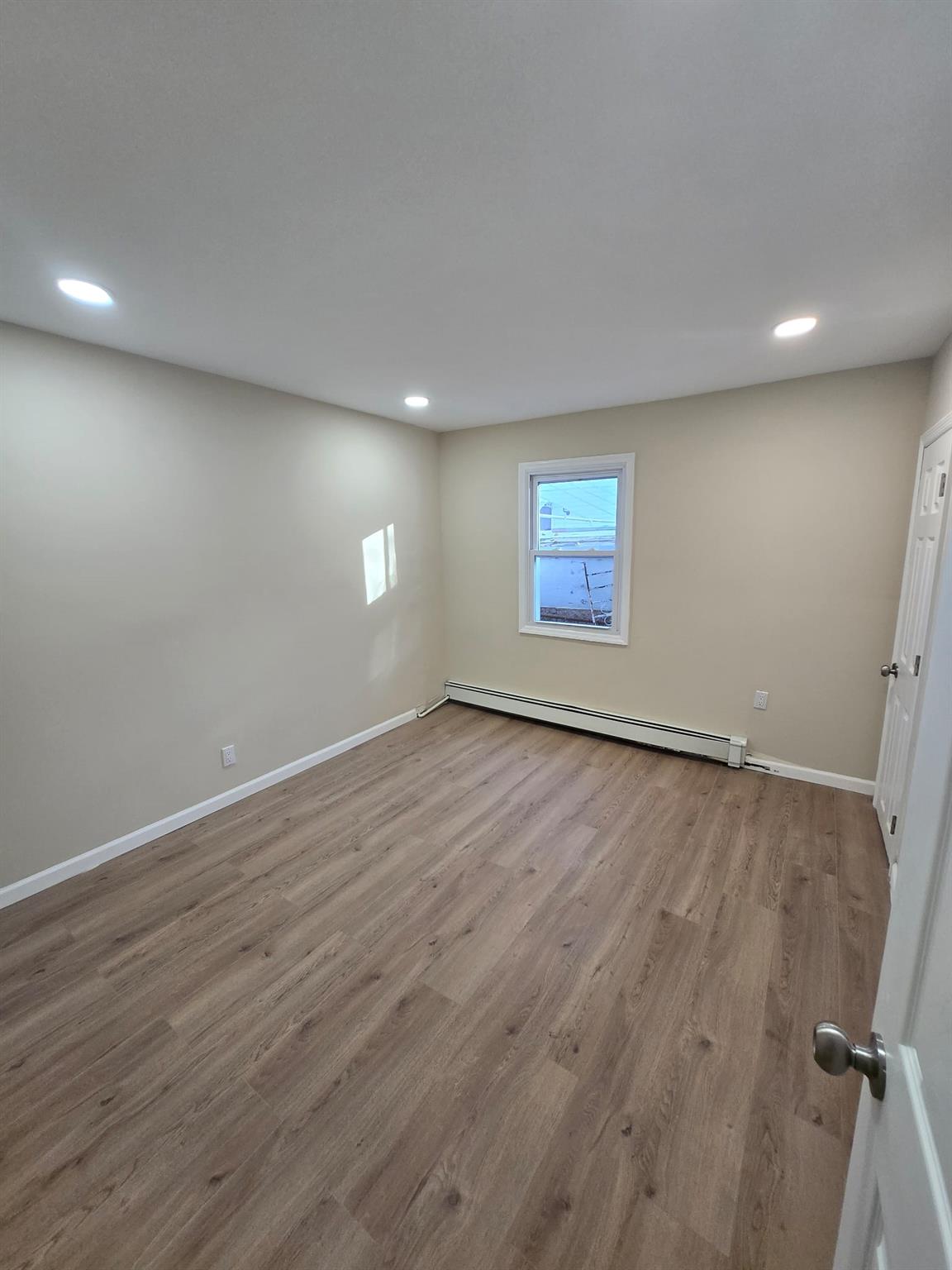 35-14 109th Street Queens, NY 11368 - Photo 12 of 38 Below grade area with recessed lighting, wood finished floors, baseboards, and baseboard heating