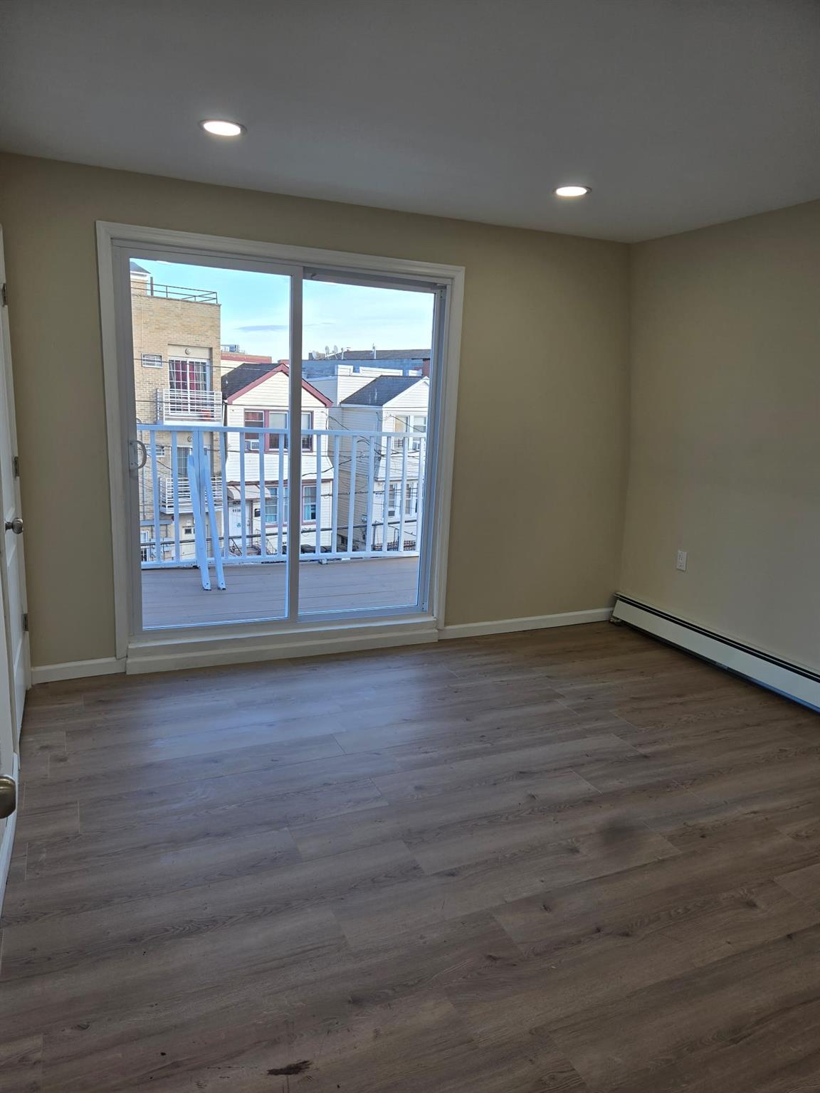 35-14 109th Street Queens, NY 11368 - Photo 18 of 38 Spare room with baseboard heating, baseboards, wood finished floors, and recessed lighting
