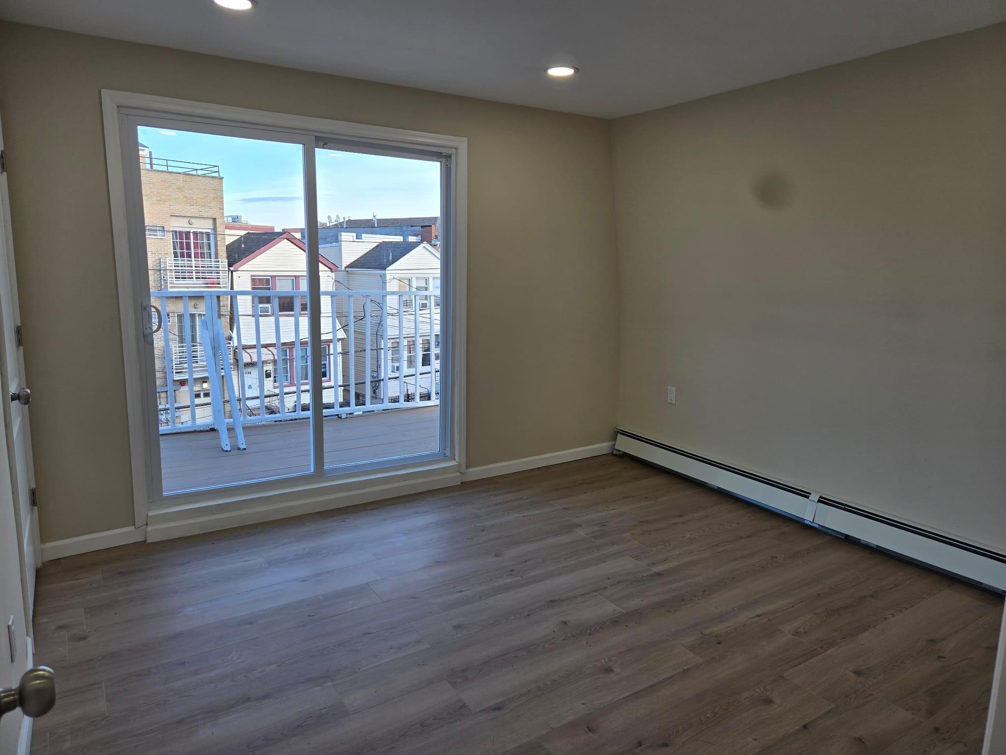 35-14 109th Street Queens, NY 11368 - Photo 22 of 38 Spare room featuring a baseboard heating unit, wood finished floors, baseboards, and recessed lighting