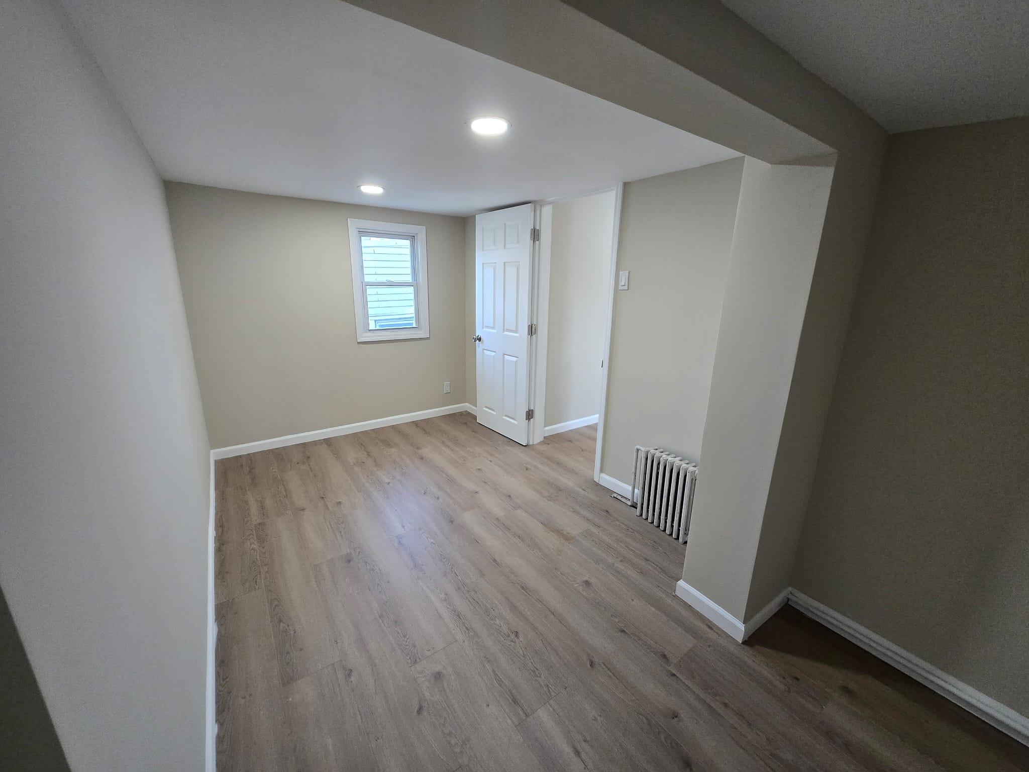 35-14 109th Street Queens, NY 11368 - Photo 26 of 38 Below grade area with recessed lighting, radiator, wood finished floors, and baseboards