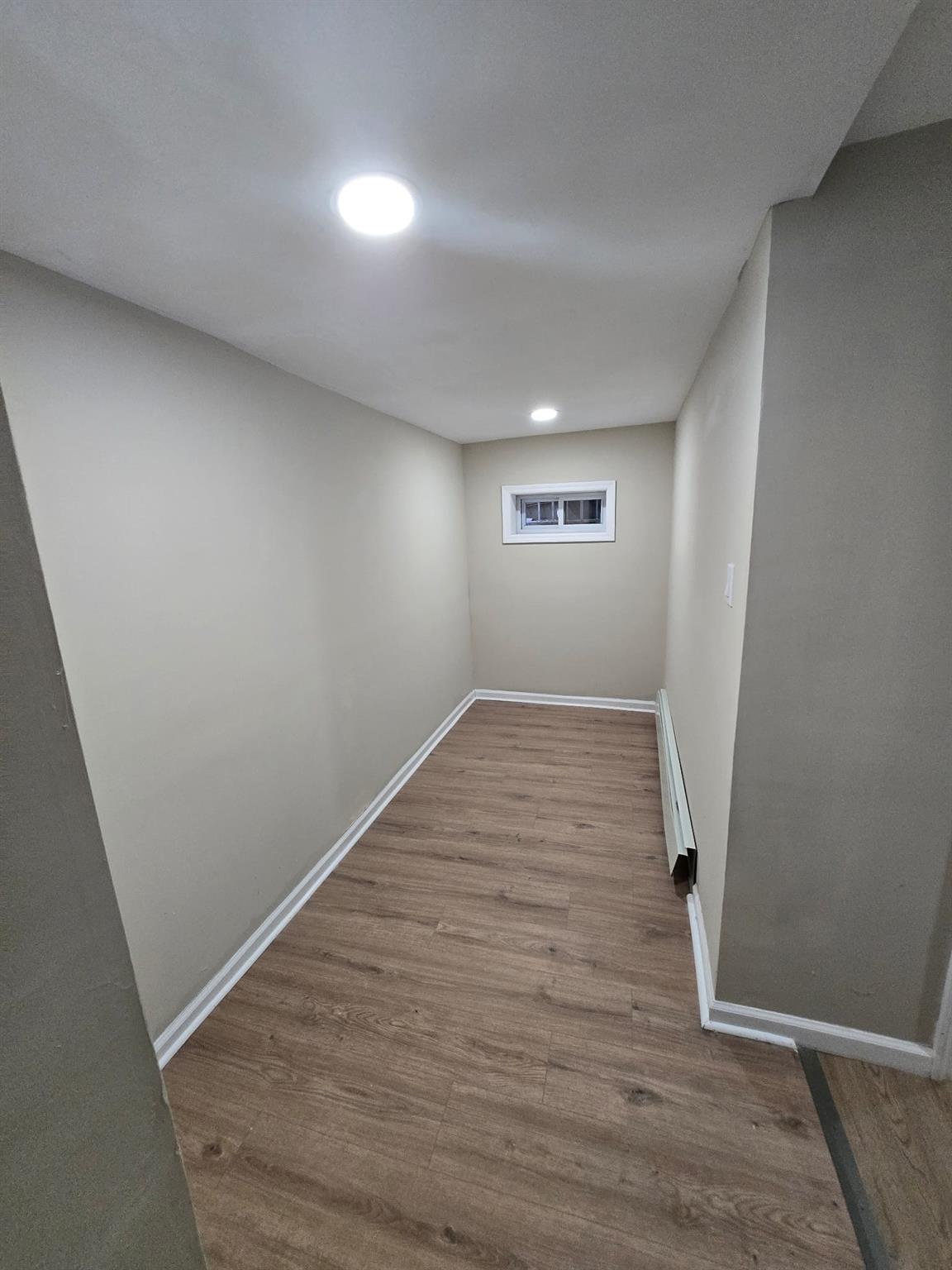 35-14 109th Street Queens, NY 11368 - Photo 33 of 38 Finished below grade area featuring a baseboard heating unit, wood finished floors, baseboards, and recessed lighting