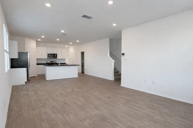 a view of kitchen with kitchen island a sink wooden floor and stainless steel appliances