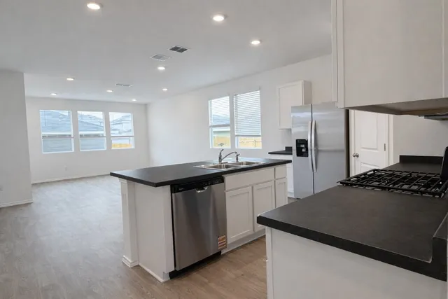 a kitchen with granite countertop a sink a stove and refrigerator