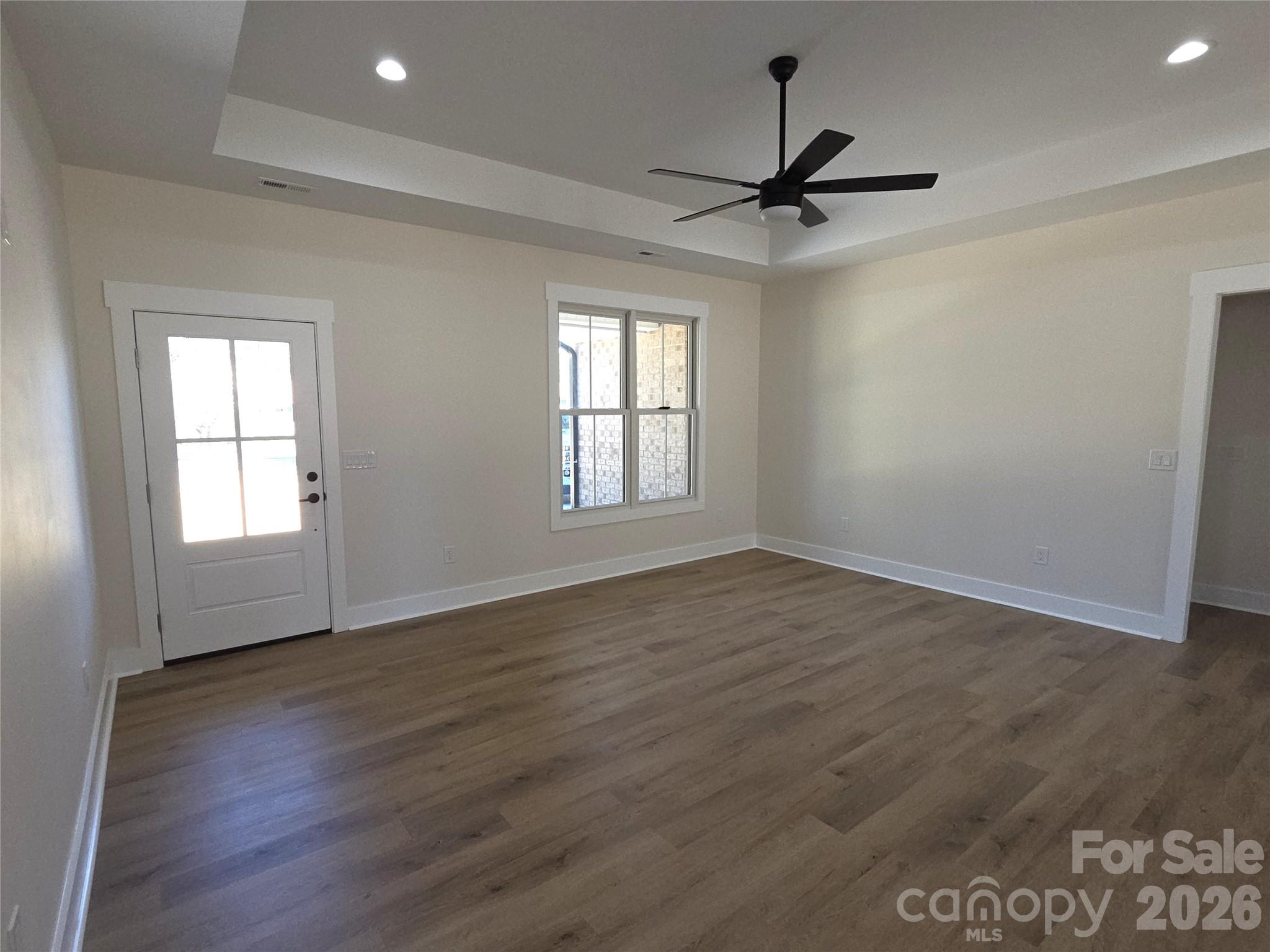 613 Bethany Road Albemarle, NC 28001 - Photo 3 of 26 an empty room with wooden floor ceiling fan and windows