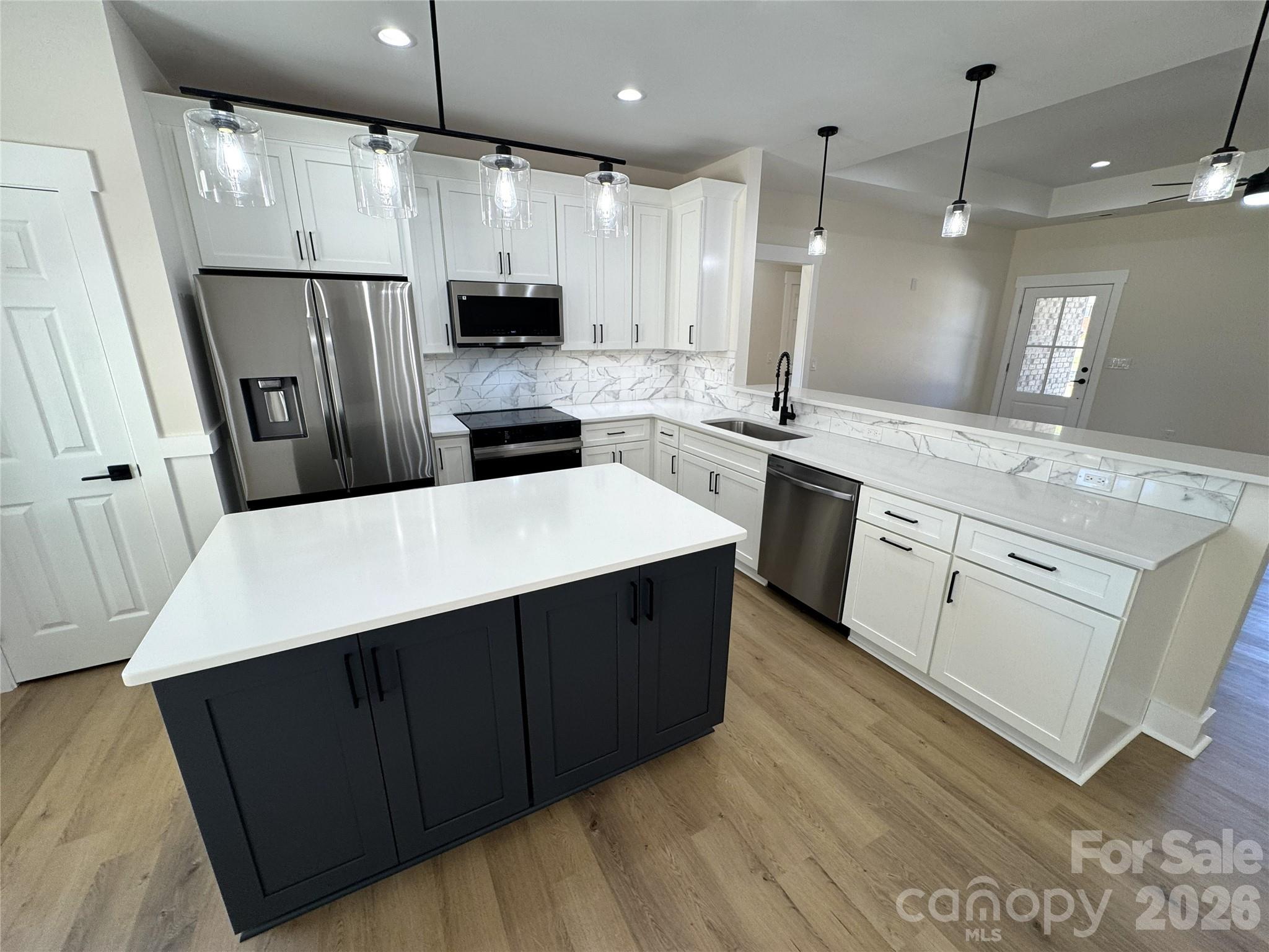 613 Bethany Road Albemarle, NC 28001 - Photo 9 of 26 a kitchen with stainless steel appliances kitchen island granite countertop a refrigerator a sink dishwasher a stove and white cabinets with wooden floor