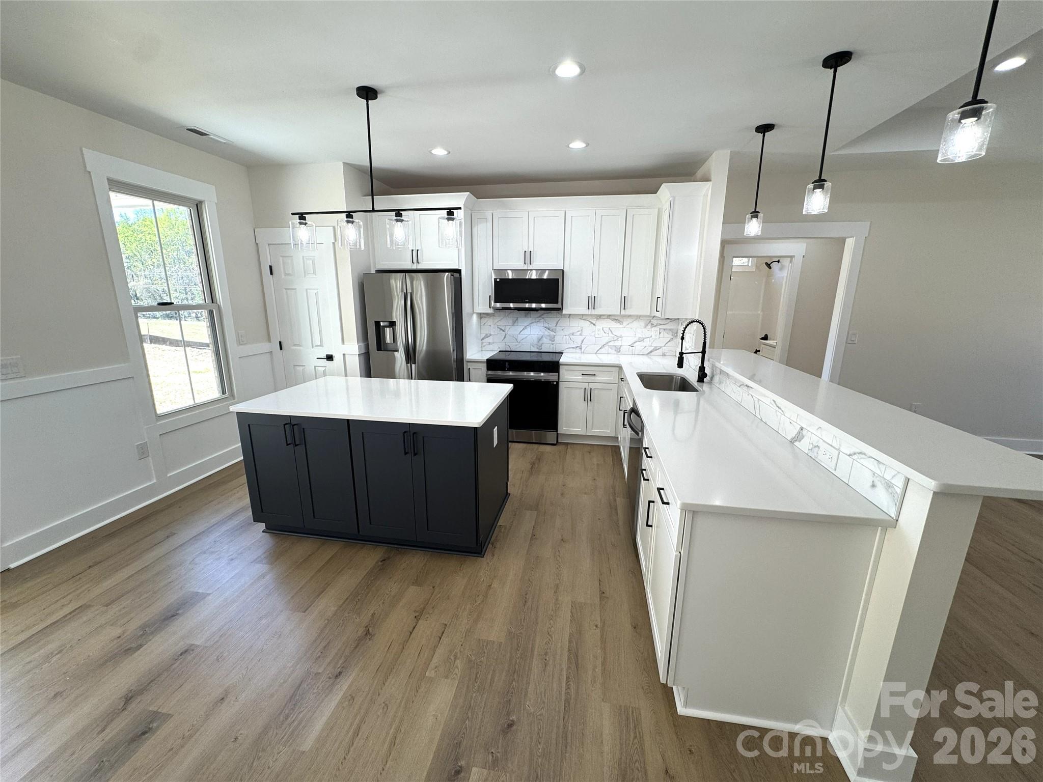 613 Bethany Road Albemarle, NC 28001 - Photo 10 of 26 a large kitchen with stainless steel appliances kitchen island a large counter space a sink a window and cabinets