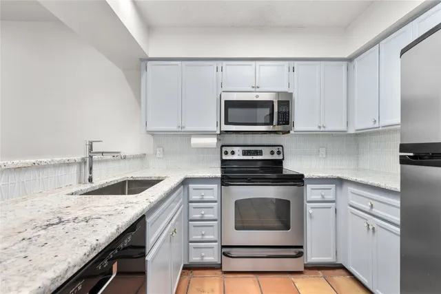 a kitchen with granite countertop a sink stove and microwave