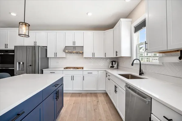 a kitchen with stainless steel appliances granite countertop a stove a refrigerator a sink dishwasher a oven and a dining table with wooden floor