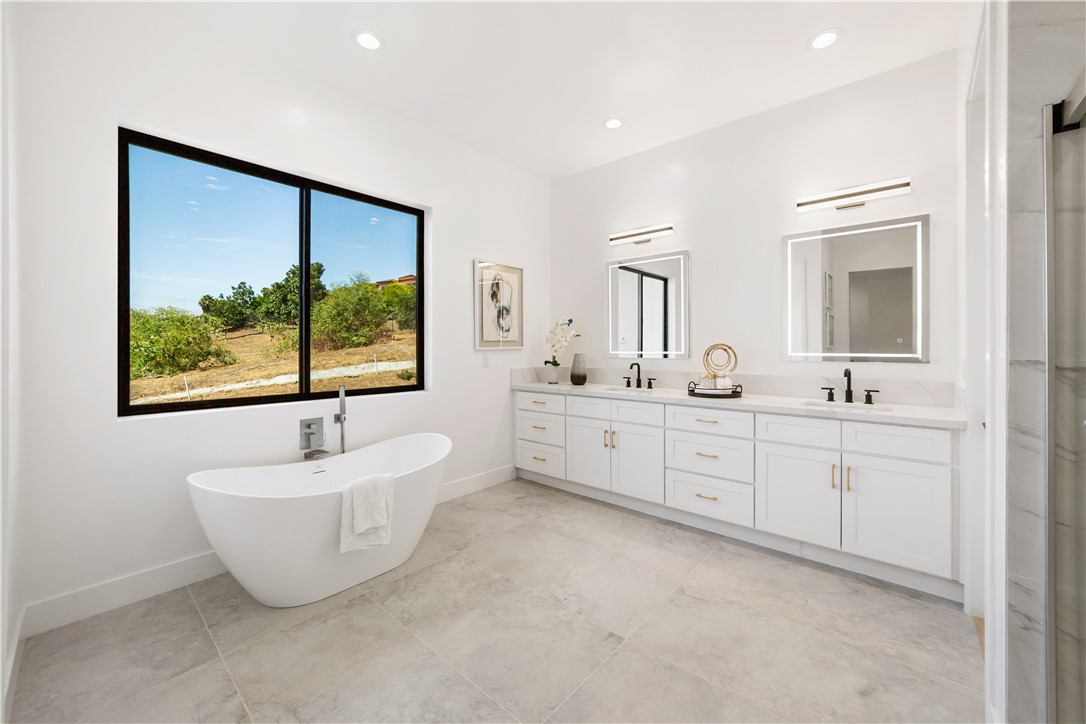 2027 Vía Monserate Fallbrook, CA 92028 - Photo 12 of 66 a bathroom with a double vanity sink a large mirror and a bathtub