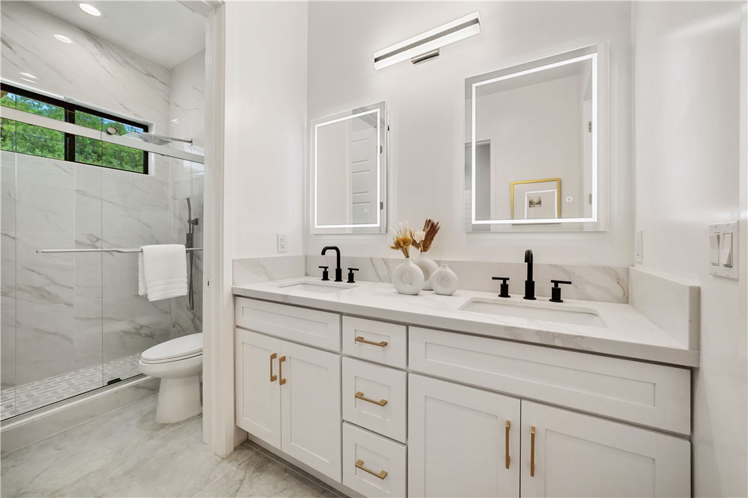 2027 Vía Monserate Fallbrook, CA 92028 - Photo 19 of 66 a bathroom with a double vanity sink toilet and a mirror