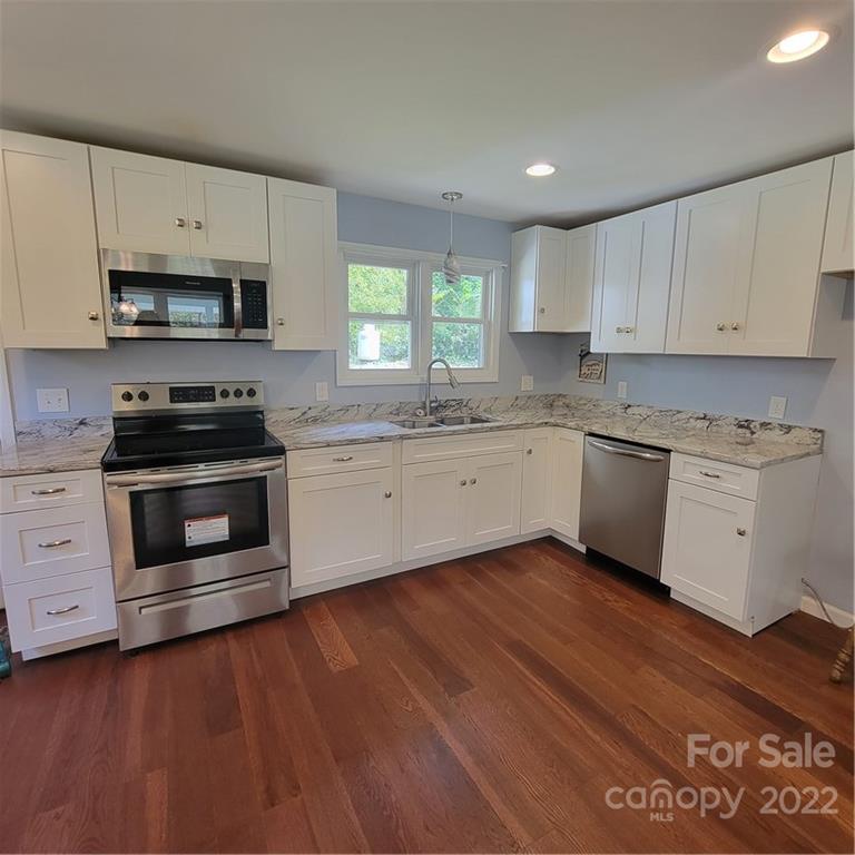 26 Possum Trot Road Bakersville, NC 28705 - Photo 11 of 22 a kitchen with stainless steel appliances a stove a sink and white cabinets