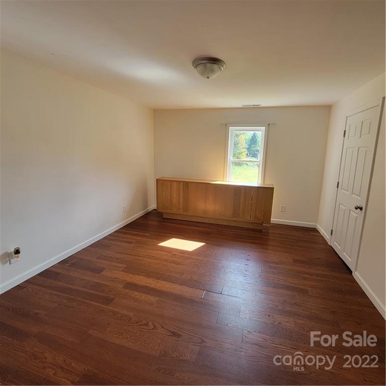 26 Possum Trot Road Bakersville, NC 28705 - Photo 16 of 22 an empty room with wooden floor and windows