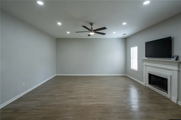 an empty room with fireplace flat screen tv and wooden floor