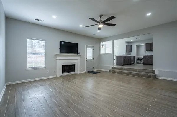 a view of a livingroom with a fireplace a ceiling fan and windows
