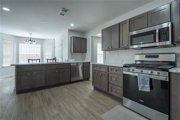 a kitchen with stainless steel appliances granite countertop a stove a sink and a microwave