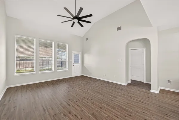 an empty room with wooden floor and windows