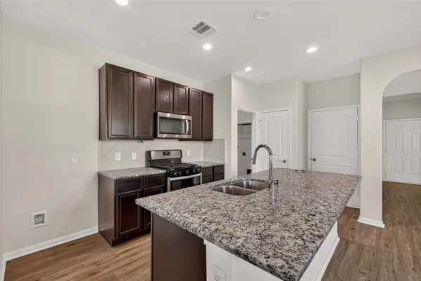 a kitchen with granite countertop kitchen island stainless steel appliances a sink stove and cabinets