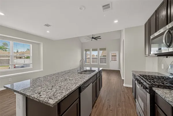 a kitchen with granite countertop wooden cabinets stainless steel appliances and a wooden floor