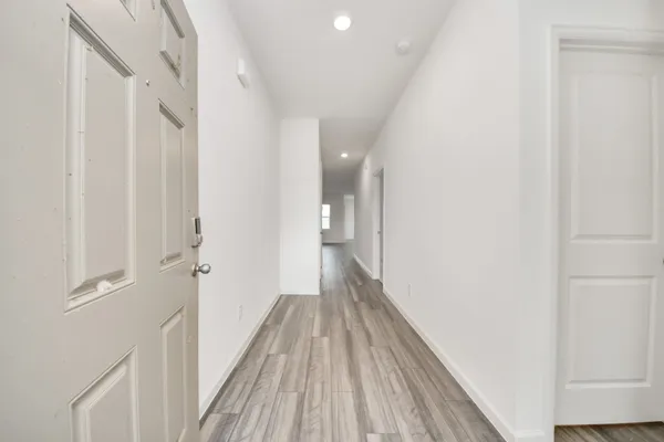 a view of a hallway with wooden floor and a bathroom