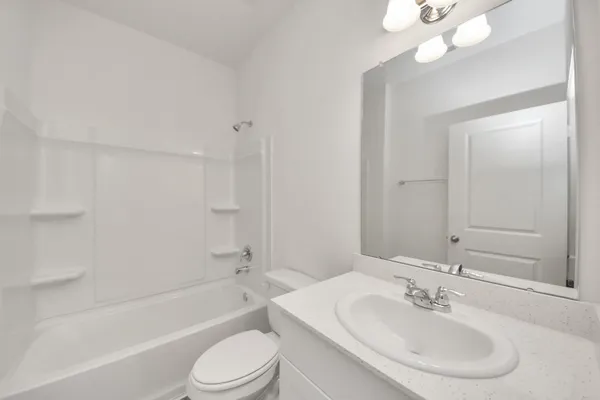 a bathroom with a bathtub shower sink vanity mirror and toilet