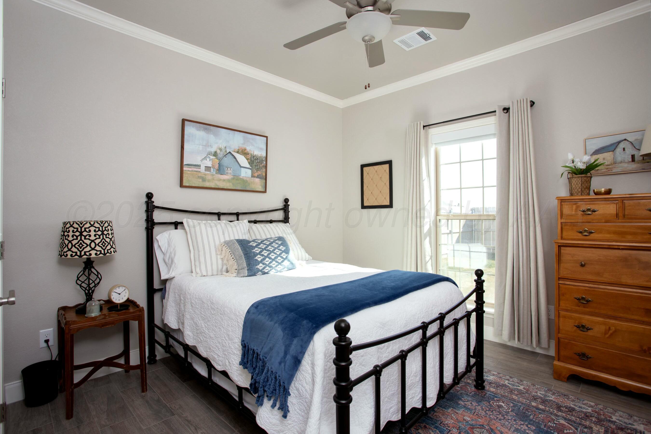 18501 Helium Road Canyon, TX 79015 - Photo 20 of 28 a bedroom with a bed and a chandelier