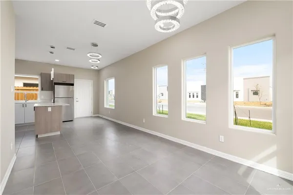 a view of an empty room with a window and kitchen view