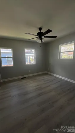 an empty room with wooden floor fan and windows