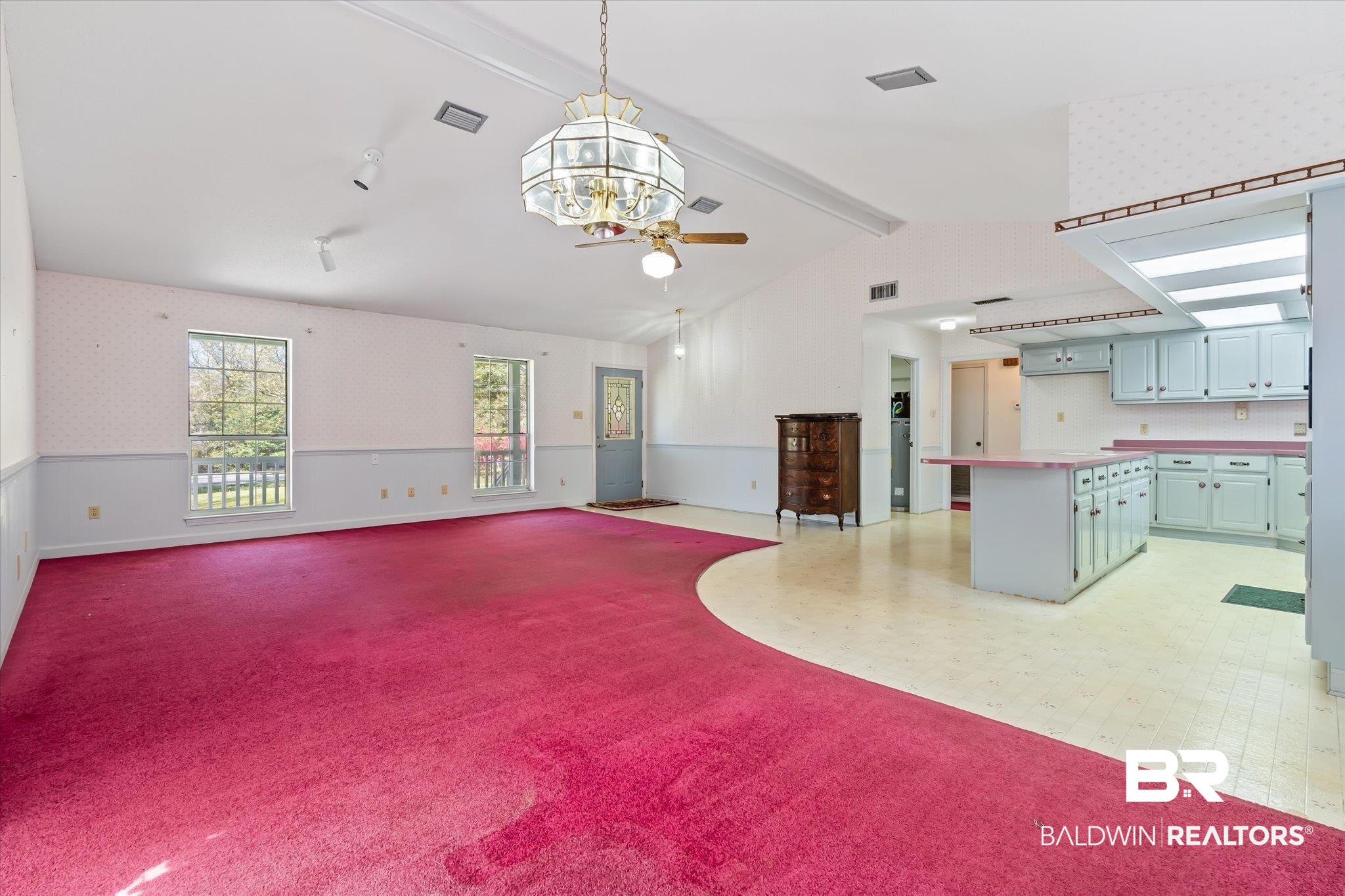 6030 Lott Road Eight Mile, AL 36613 - Photo 5 of 21 Unfurnished living room featuring light colored carpet, ceiling fan with notable chandelier, a wainscoted wall, wallpapered walls, and vaulted ceiling with beams