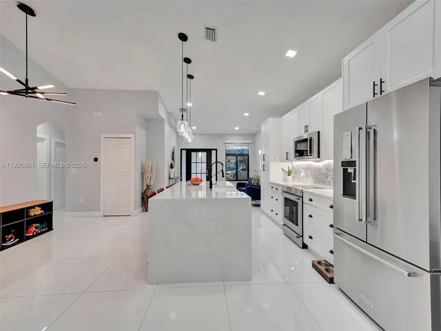 a large white kitchen with refrigerator stove and a fireplace