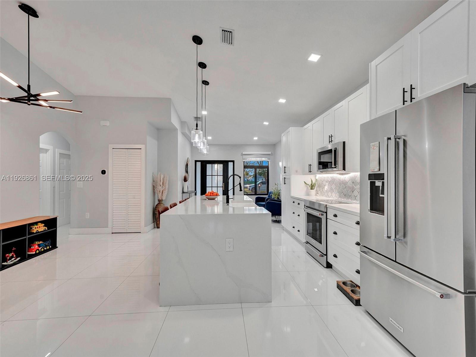 19901 Northwest 77th Court Hialeah, FL 33015 - Photo 14 of 50 a large white kitchen with refrigerator stove and a fireplace