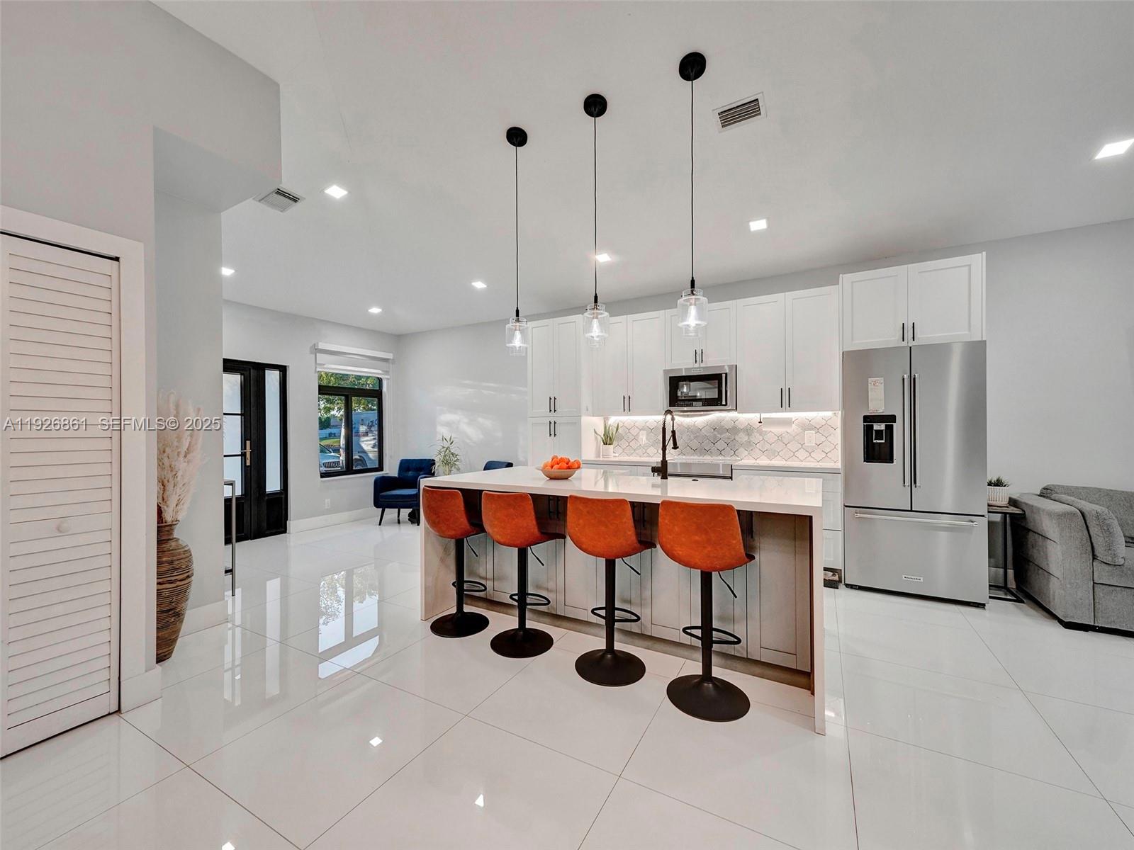 19901 Northwest 77th Court Hialeah, FL 33015 - Photo 15 of 50 a kitchen with stainless steel appliances kitchen island granite countertop a table chairs in it and white cabinets