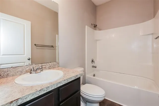 a bathroom with a granite countertop sink a toilet and shower