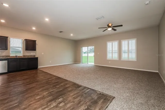 a view of an empty room with a window and a kitchen