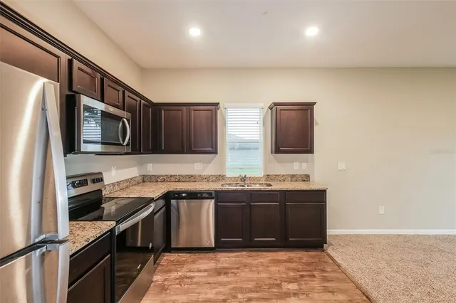 a kitchen with stainless steel appliances granite countertop a sink stove and microwave