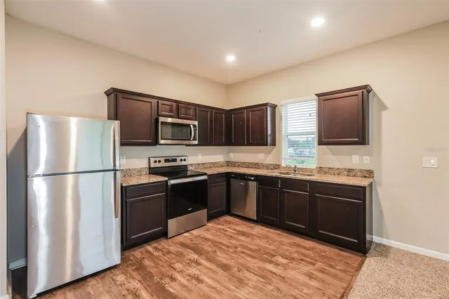 a kitchen with stainless steel appliances granite countertop a refrigerator stove a sink dishwasher and microwave