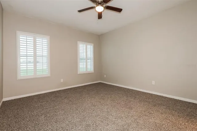 an empty room with windows and fan
