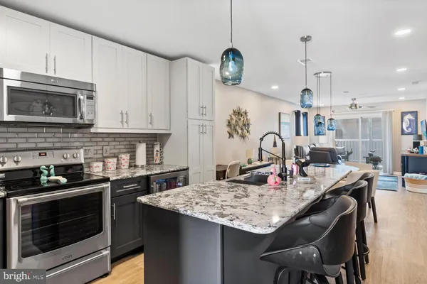 a kitchen with granite countertop a stove a microwave a dining table and chairs