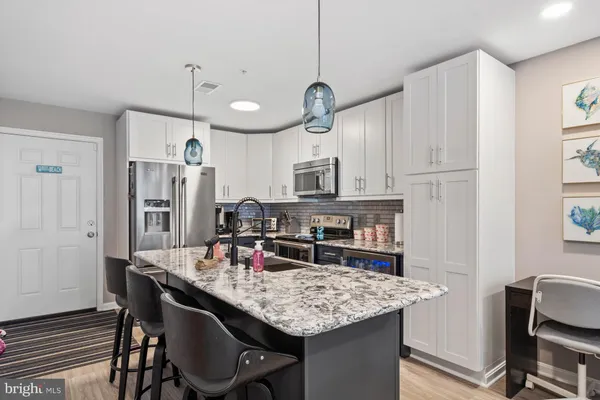 a kitchen with kitchen island granite countertop a table chairs stainless steel appliances and cabinets