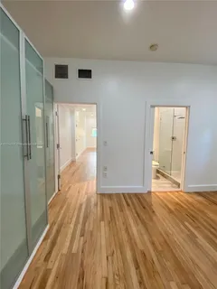 a view of a hallway with wooden floor and a bathroom